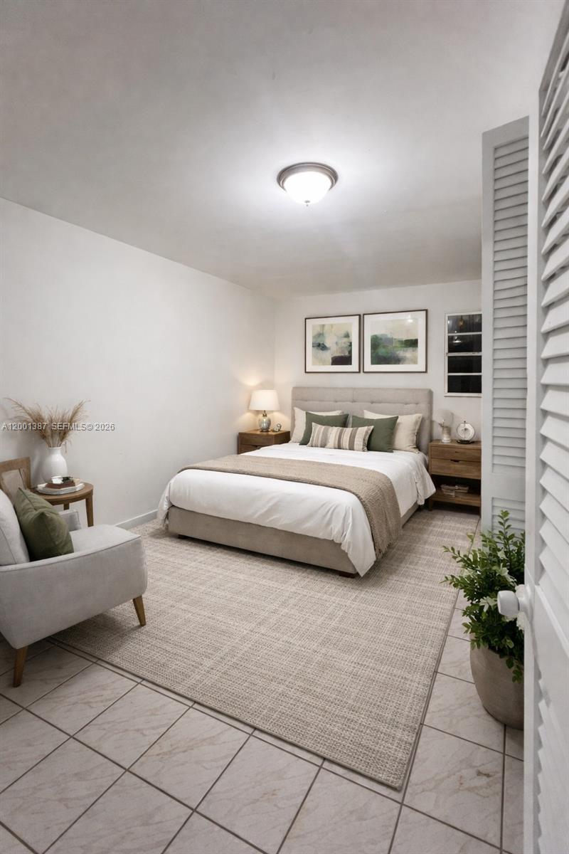 A bedroom features a queen bed, a gray armchair, and tile flooring — 413 NW 33rd St # A, Miami FL 33127, MIAMI, FL