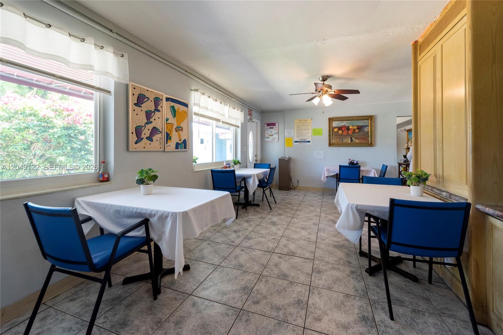 A dining room features tiled floors, several tables with white tablecloths, and blue chairs — 1930 Lincoln St, Hollywood FL 33020, HOLLYWOOD, FL
