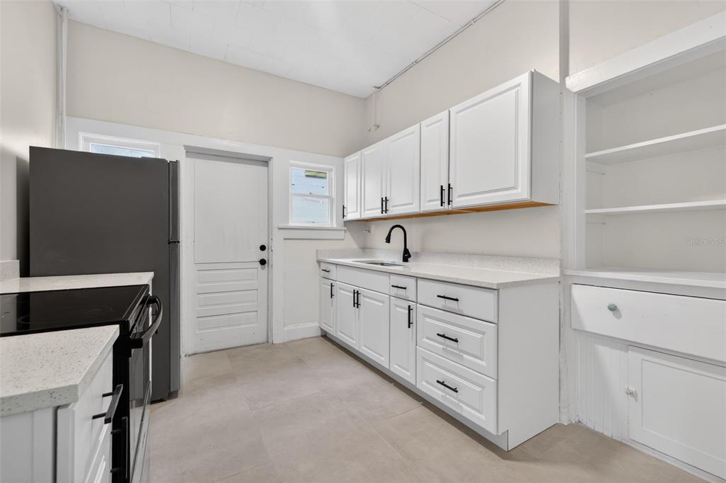 A kitchen features white cabinets, light countertops, a dark faucet, and a black refrigerator — 633 7TH AVENUE N, ST PETERSBURG, FL