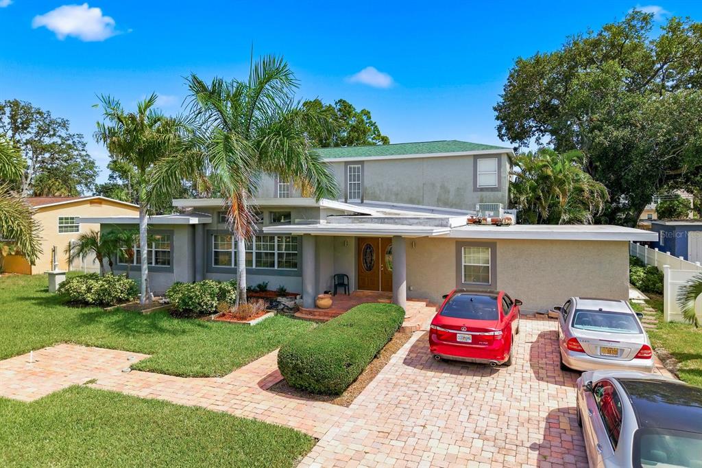 A two-story house with a paved driveway, palm trees, and a green roof — 850 36TH AVENUE S, ST PETERSBURG, FL