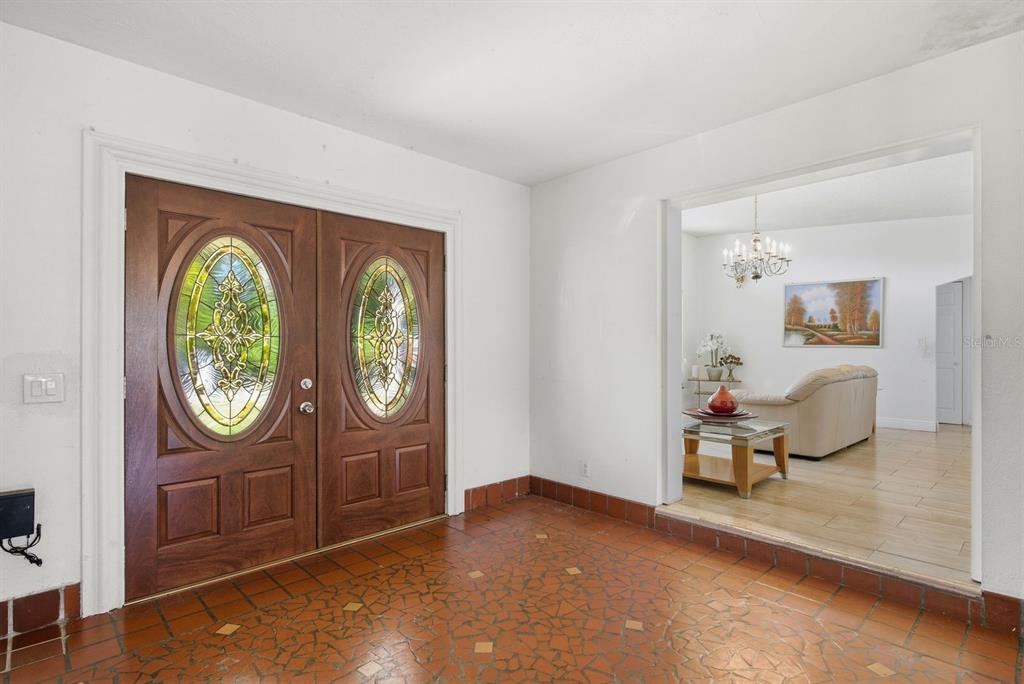An entryway with a double wood door featuring stained glass panels and terracotta tile flooring — 850 36TH AVENUE S, ST PETERSBURG, FL