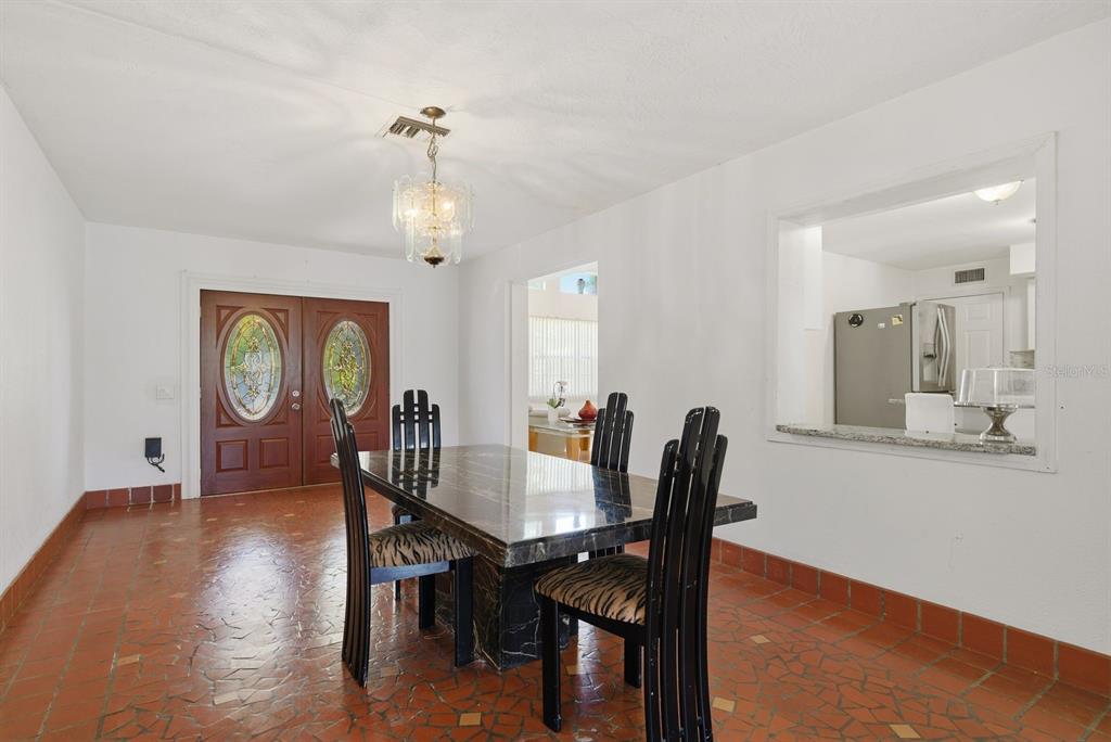 A dining room with a marble table, black chairs, and terracotta tile flooring — 850 36TH AVENUE S, ST PETERSBURG, FL