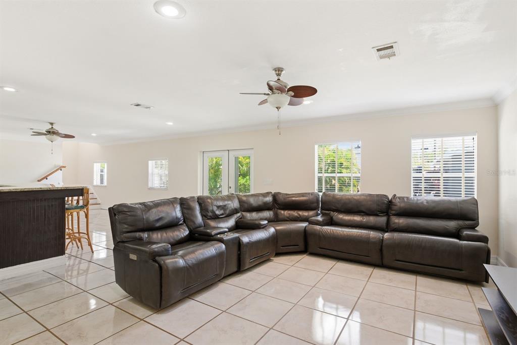 A living room with a large dark leather sectional sofa and light-colored tile flooring — 850 36TH AVENUE S, ST PETERSBURG, FL
