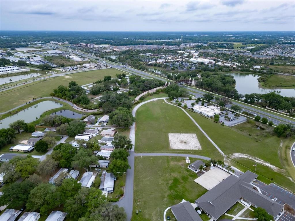 An aerial view shows a residential area with mobile homes, green fields, and a nearby highway — Lot 56 Blk C LEXINGTON DRIVE, WILDWOOD, FL
