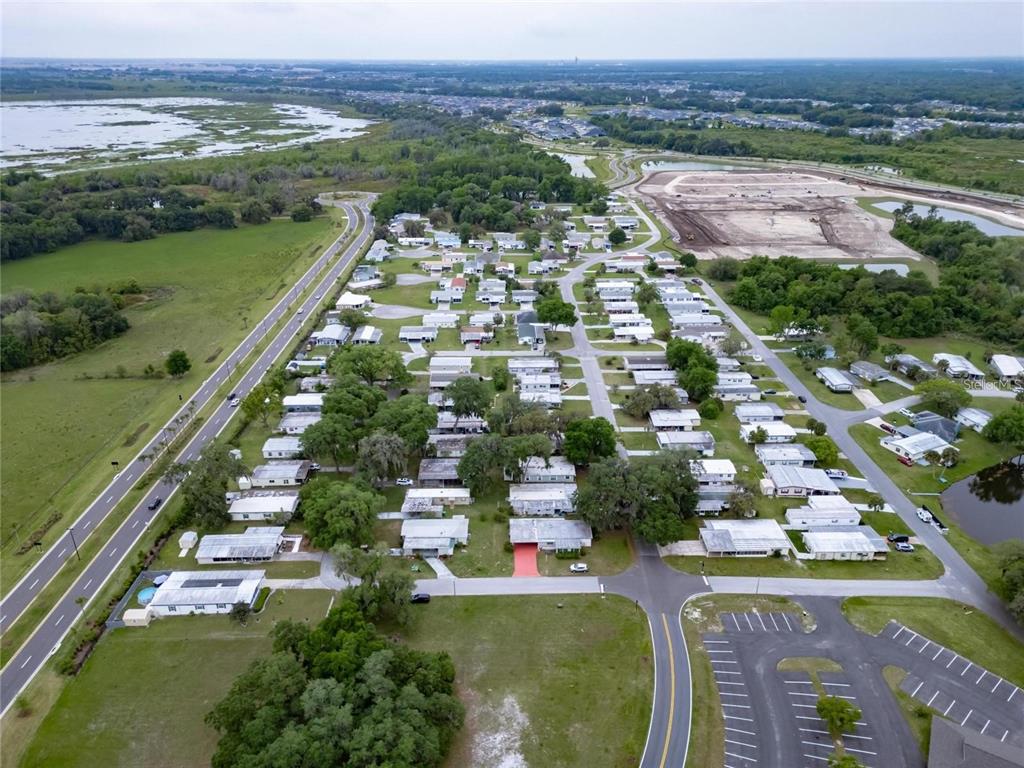 An aerial view shows a mobile home community situated next to a highway and wetlands — Lot 56 Blk C LEXINGTON DRIVE, WILDWOOD, FL
