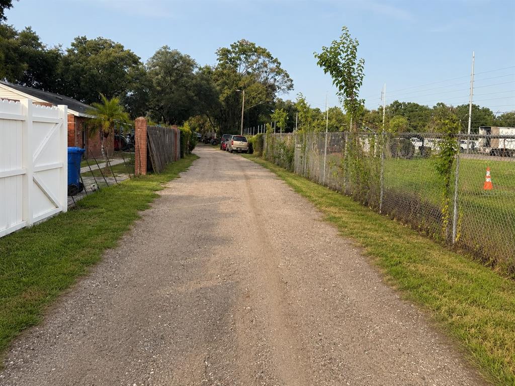 A gravel driveway leads past a white fence and a chain-link fence toward parked vehicles — 2504 S 54TH STREET, TAMPA, FL