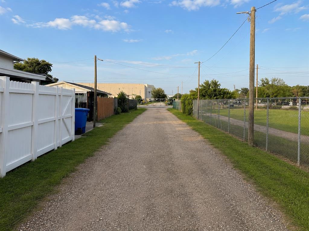 A gravel alleyway runs between a white vinyl fence and a chain-link fence — 2504 S 54TH STREET, TAMPA, FL