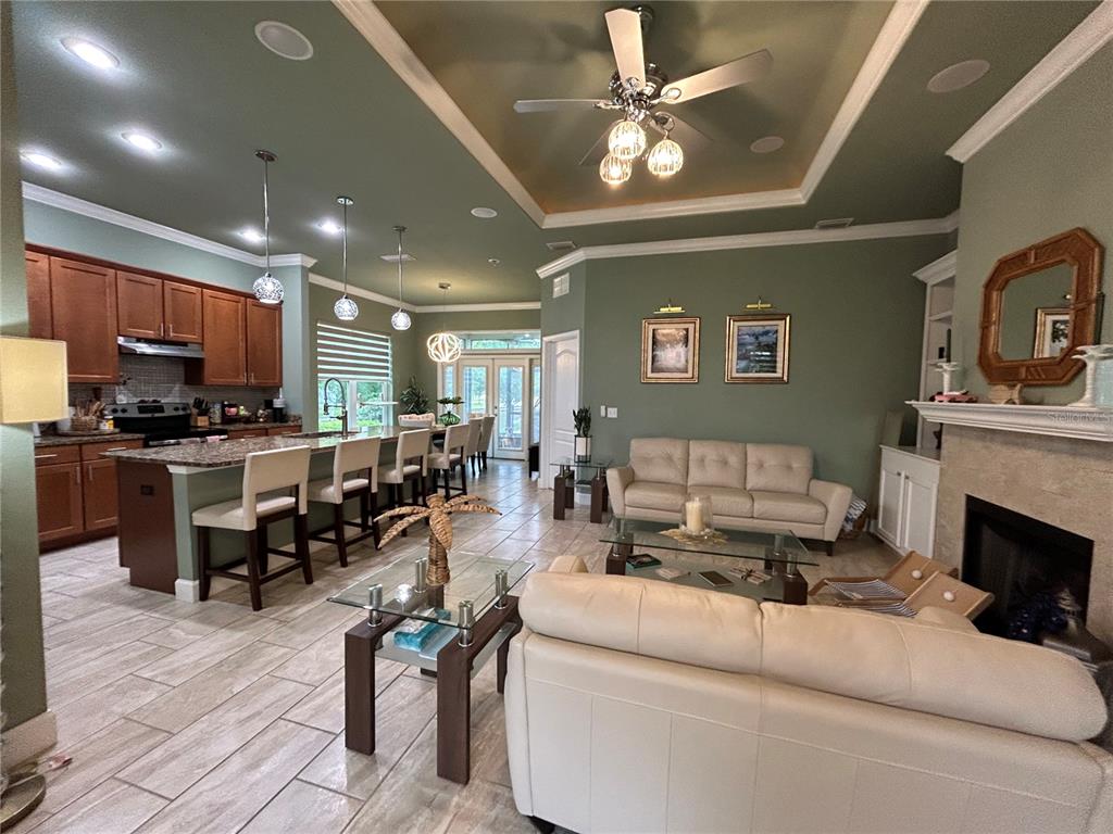 An open-concept kitchen and living room featuring sage green walls, tile flooring, and a fireplace — 11788 SW 30TH AVENUE, GAINESVILLE, FL