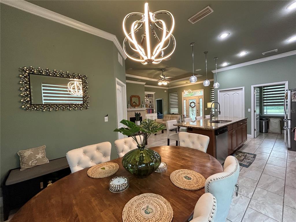 A dining area with a round wooden table and tufted chairs opens into a kitchen — 11788 SW 30TH AVENUE, GAINESVILLE, FL