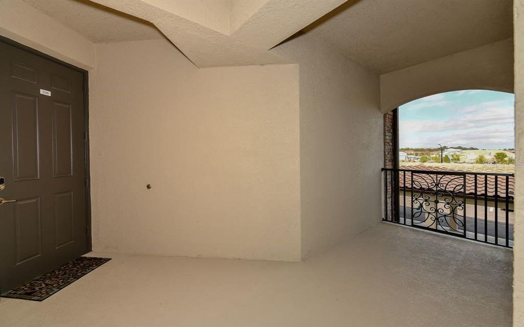 A covered balcony features a brown door, beige walls, and a decorative metal railing — 17006 VARDON TERRACE UNIT 208, BRADENTON, FL
