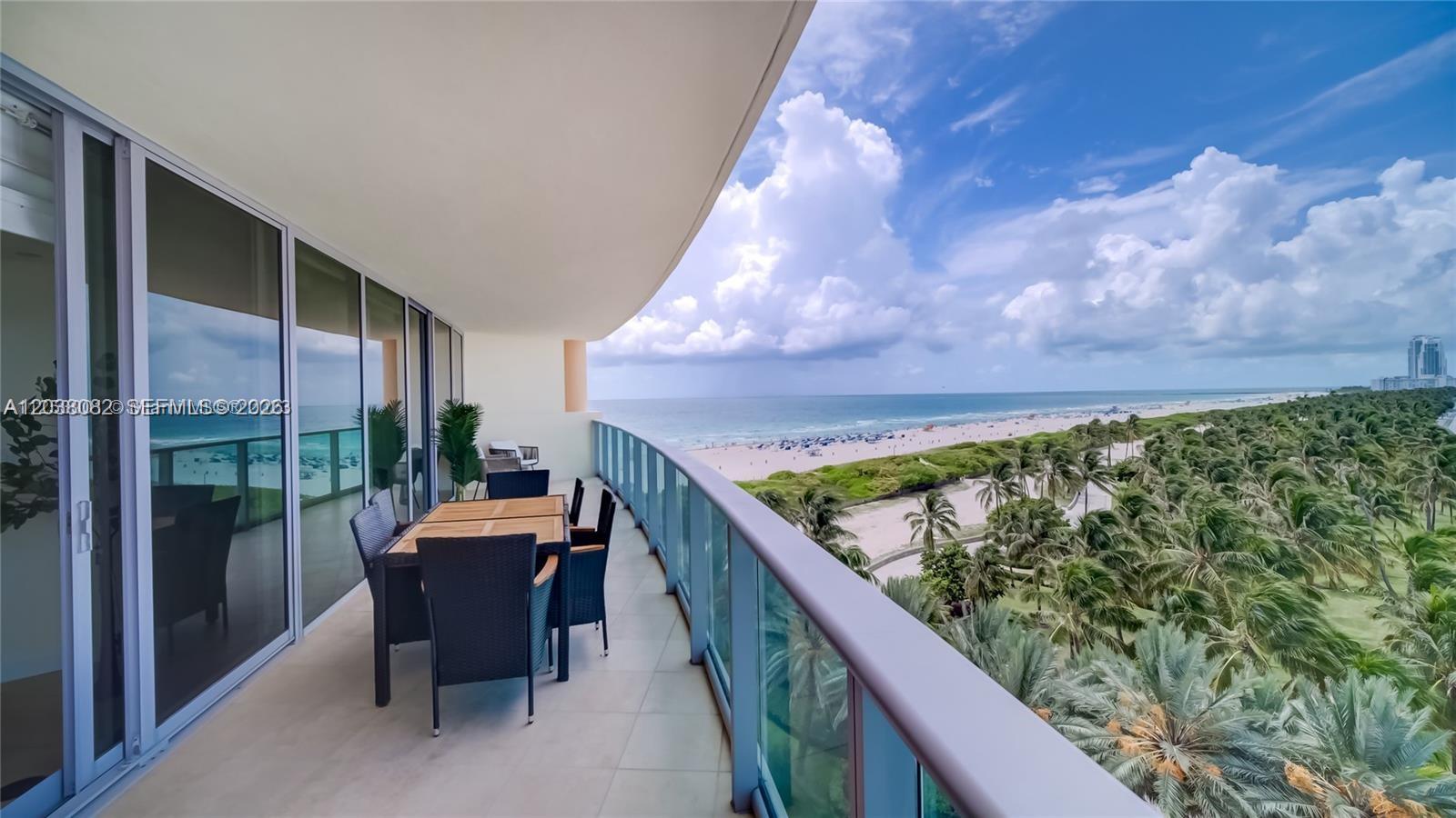 A balcony with a dining set overlooks a beach, ocean, and palm trees — 1455 Ocean Dr # 902, Miami Beach FL 33139, MIAMI BEACH, FL