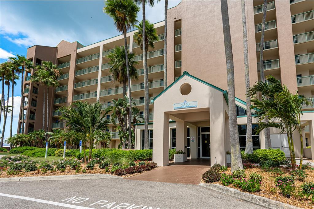 The exterior of a multi-story tan apartment building features a covered entrance and palm trees — 2320 TERRA CEIA BAY BOULEVARD UNIT 108, PALMETTO, FL