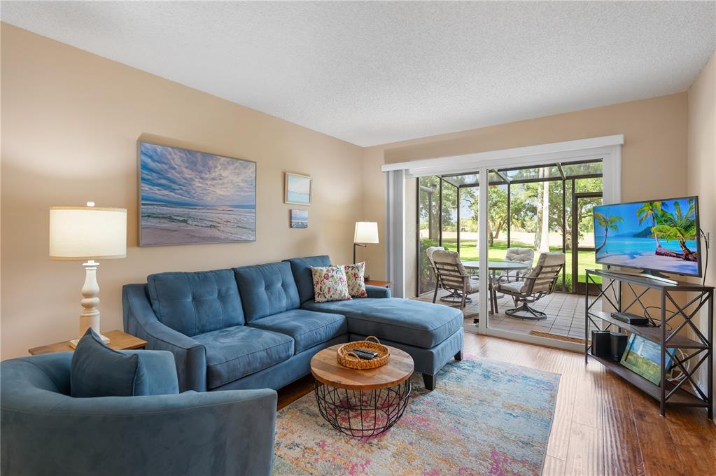 A living room features a blue sectional sofa, a round coffee table, and a sliding door — 2320 TERRA CEIA BAY BOULEVARD UNIT 108, PALMETTO, FL