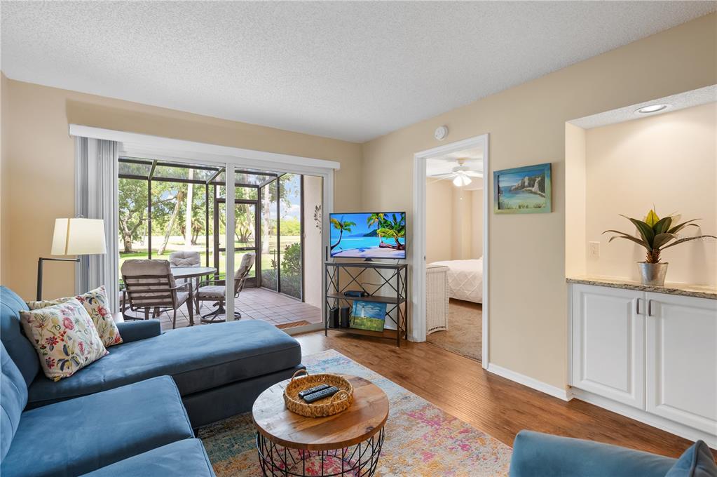 A living room features a blue sectional sofa, a coffee table, and a sliding glass door — 2320 TERRA CEIA BAY BOULEVARD UNIT 108, PALMETTO, FL
