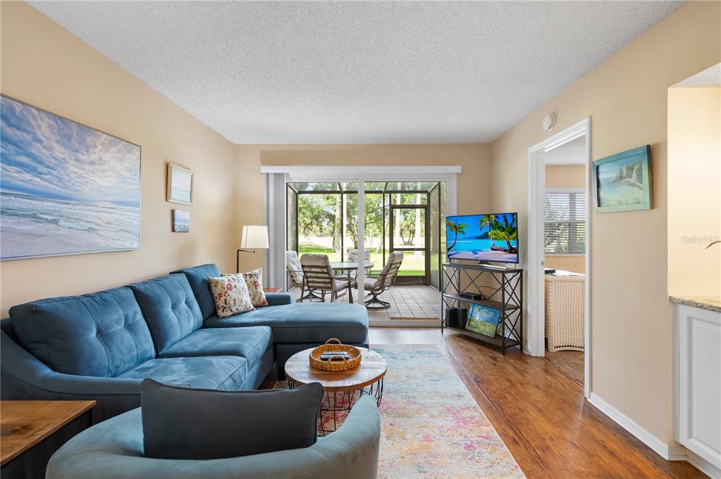 A living room features a blue sectional sofa, a round coffee table, and a screened patio — 2320 TERRA CEIA BAY BOULEVARD UNIT 108, PALMETTO, FL