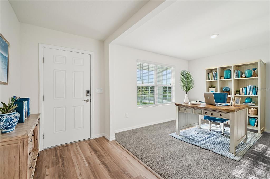 A home office features a desk, shelving, carpeted flooring, and a white entry door — 8914 SW 46TH AVENUE, OCALA, FL