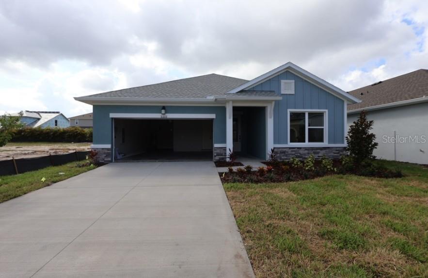 A blue single-story house with a two-car garage, stone accents, and a concrete driveway — 5133 CREEK SAND DRIVE, APOLLO BEACH, FL