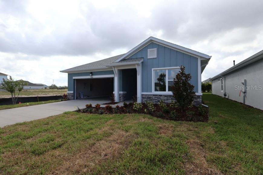 A single-story blue house with a two-car garage and stone veneer accents — 5133 CREEK SAND DRIVE, APOLLO BEACH, FL
