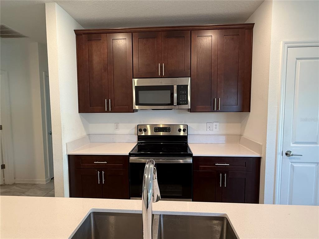 A kitchen features dark wood cabinets, stainless steel appliances, and white countertops — 558 JETT LANE, DAVENPORT, FL