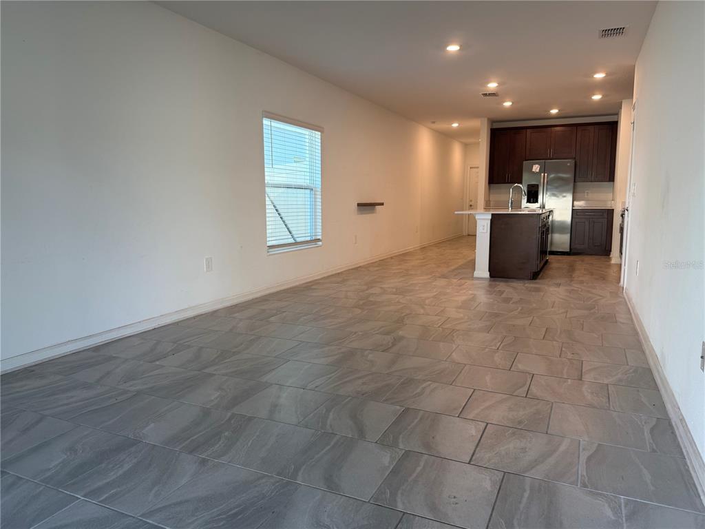 An open-concept kitchen and living area features gray tile flooring and dark wood cabinets — 558 JETT LANE, DAVENPORT, FL