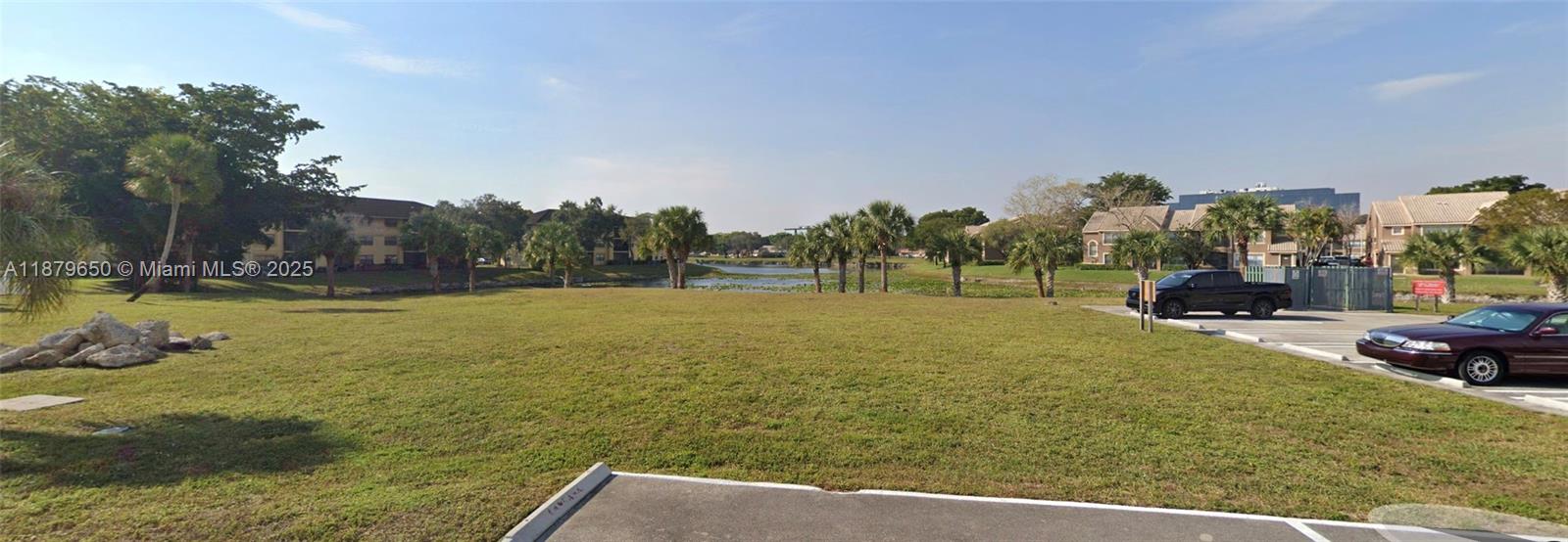 A grassy lot sits in front of a small lake surrounded by residential buildings — 28 Nw Dr, Coral Springs FL 33065, CORAL SPRINGS, FL