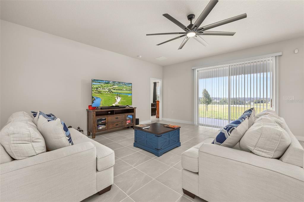A living room with two light-colored sofas, a wooden media console, and a ceiling fan — 11182 NELLIE CROSSING CIRCLE, CLERMONT, FL