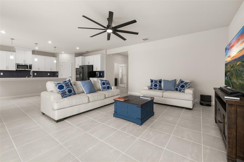 A living room with white sofas, a blue coffee table, and an open kitchen — 11182 NELLIE CROSSING CIRCLE, CLERMONT, FL