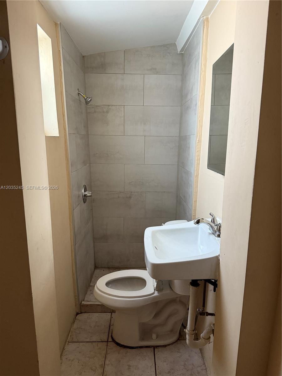 A small bathroom features a tiled shower stall, a toilet, and a wall-mounted sink — 41 SW 7th Ave # 1, Dania Beach FL 33004, DANIA BEACH, FL