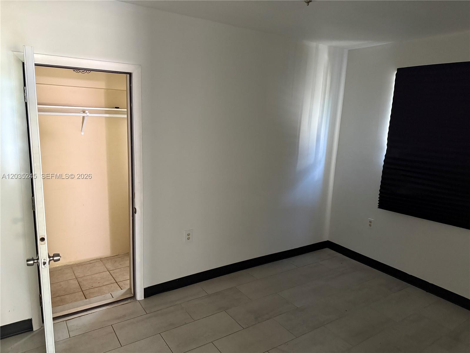 A room with light-colored tile flooring, white walls, a closet, and a dark window shade — 41 SW 7th Ave # 1, Dania Beach FL 33004, DANIA BEACH, FL