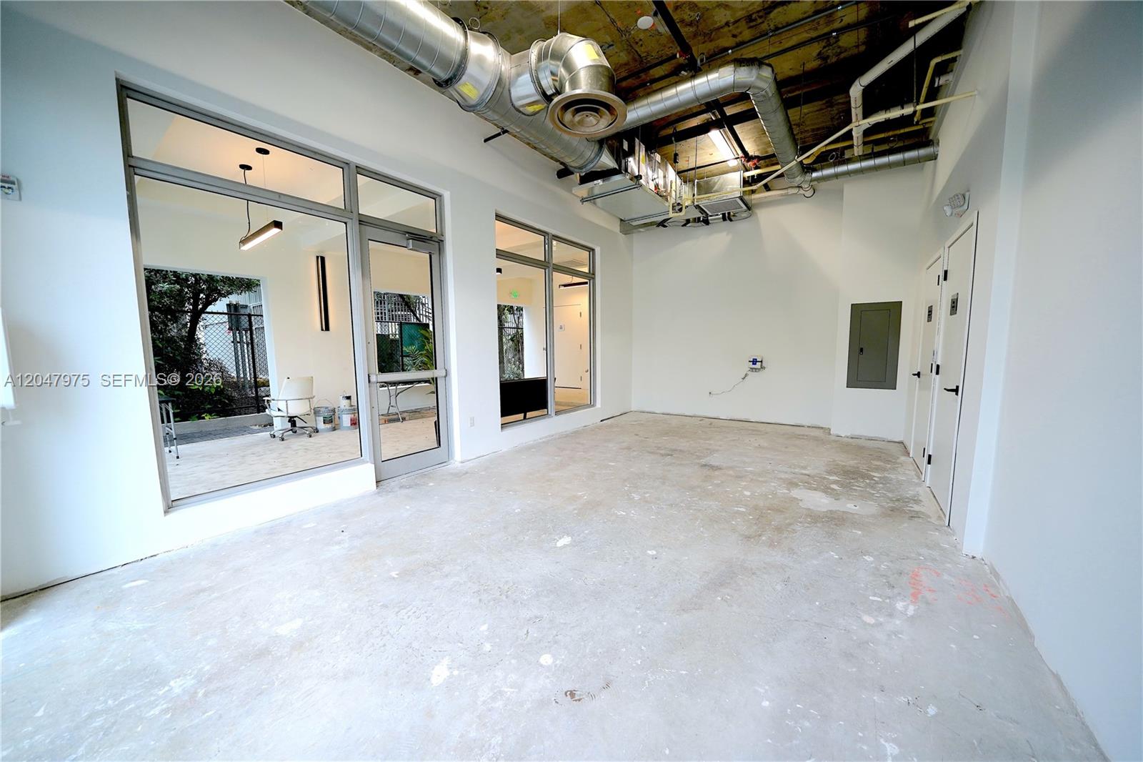 An unfinished commercial space features exposed industrial ductwork, concrete flooring, and large glass storefront windows — 650 SW 1st St # 1, Miami FL 33130, MIAMI, FL