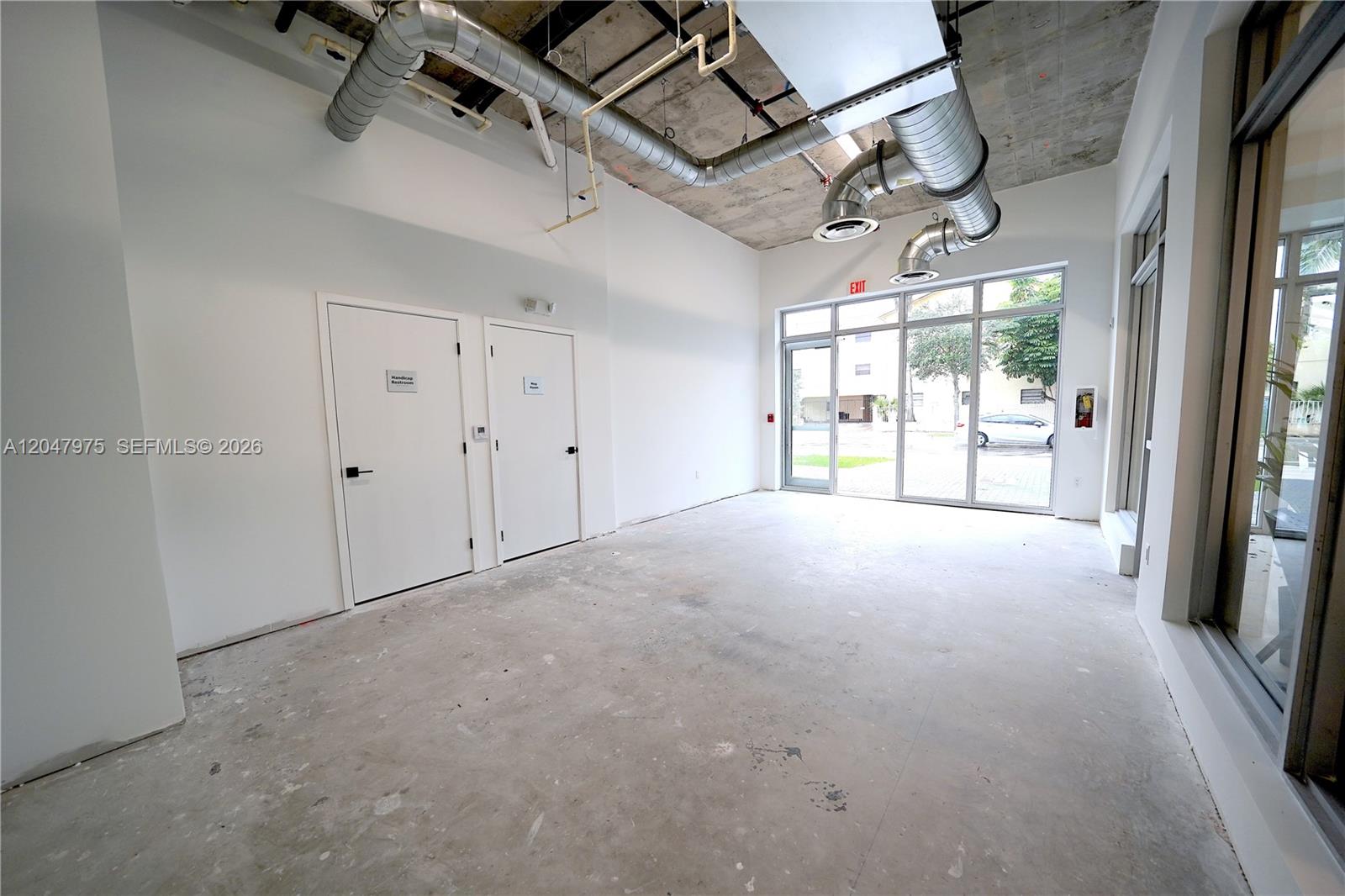 An unfinished commercial space features exposed ductwork, concrete ceilings, white walls, and large glass windows — 650 SW 1st St # 1, Miami FL 33130, MIAMI, FL