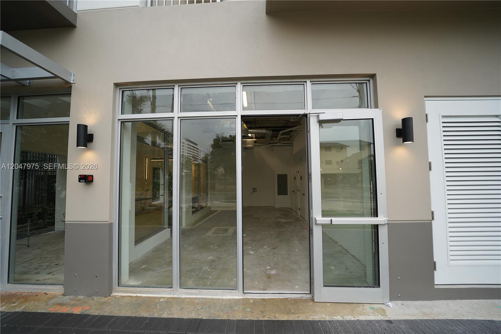 An exterior view of a commercial storefront with glass doors and a louvered side door — 650 SW 1st St # 1, Miami FL 33130, MIAMI, FL