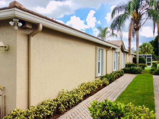 A side view of a beige stucco house with a brick walkway and landscaping — 8410 Cargill Point, West Palm Beach FL 33411, WEST PALM BEACH, FL