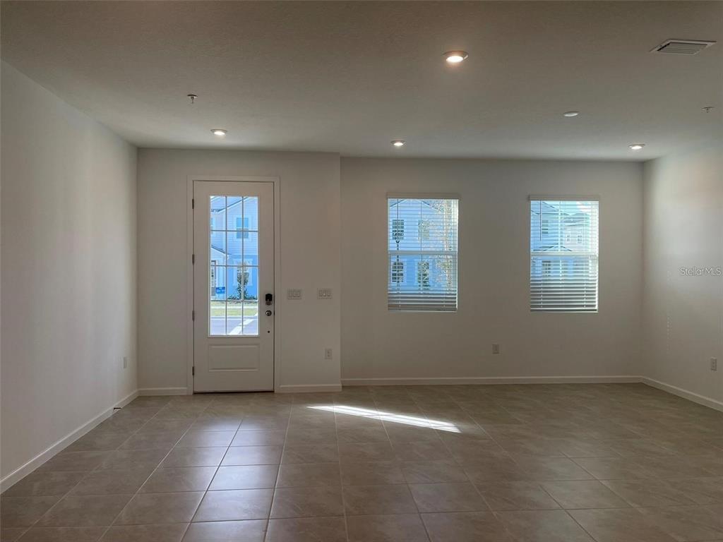 An empty room features tile flooring, white walls, a glass-paneled door, and two windows — 3107 GARDENIA RESERVE STREET, APOPKA, FL