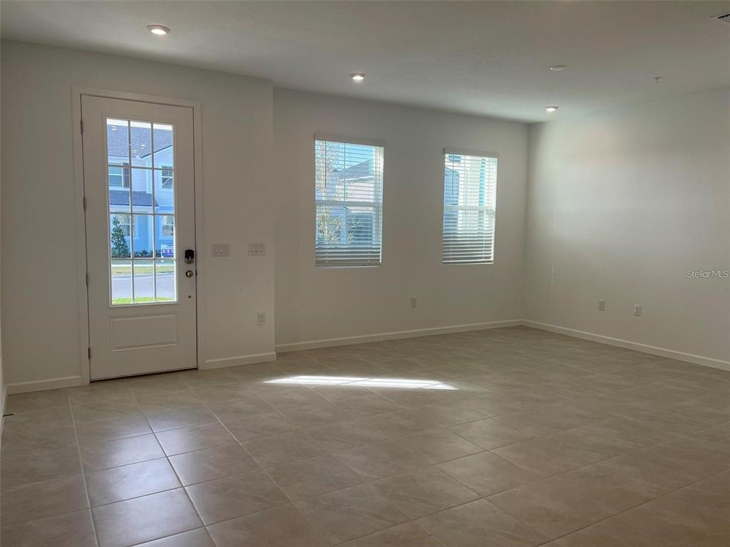 An empty room features light-colored tile flooring, white walls, two windows, and a glass-paneled door — 3107 GARDENIA RESERVE STREET, APOPKA, FL