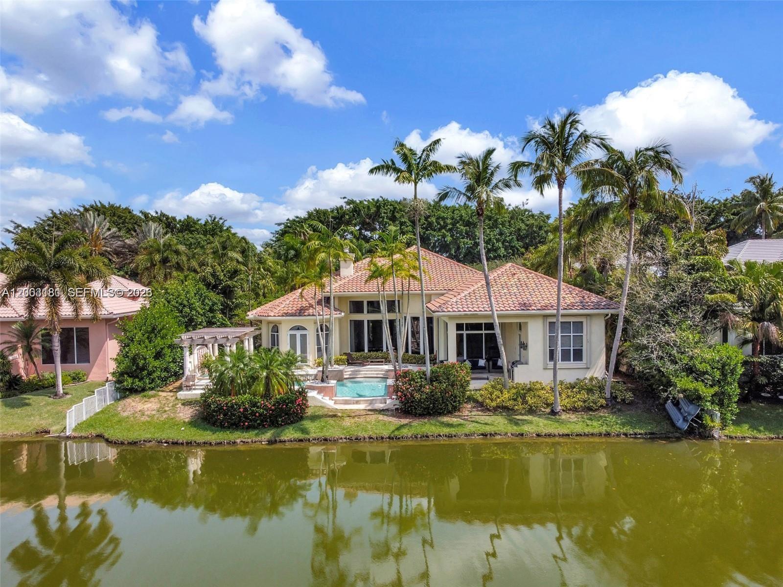 A single-story house with a tiled roof and pool sits beside a pond — 10430 Kestrel St, Plantation FL 33324, PLANTATION, FL