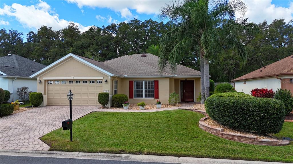 A single-story house with a beige stucco exterior, red shutters, and a paved driveway — 13322 SE 86TH CIRCLE, SUMMERFIELD, FL