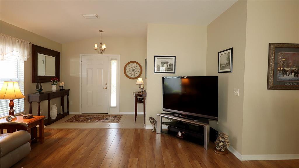 A living room features hardwood floors, a television on a stand, and an entryway door — 13322 SE 86TH CIRCLE, SUMMERFIELD, FL