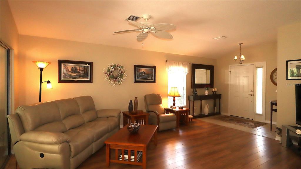 A living room features a beige sofa, wood coffee table, recliner, and wood-look flooring — 13322 SE 86TH CIRCLE, SUMMERFIELD, FL