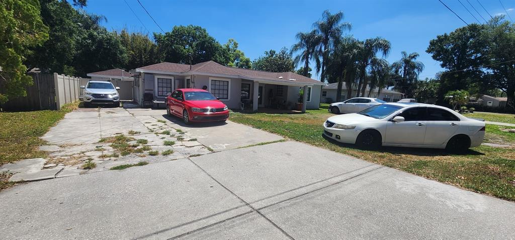 A single-story house with a concrete driveway and three parked cars in the front yard — 6809 N GUNLOCK AVENUE, TAMPA, FL