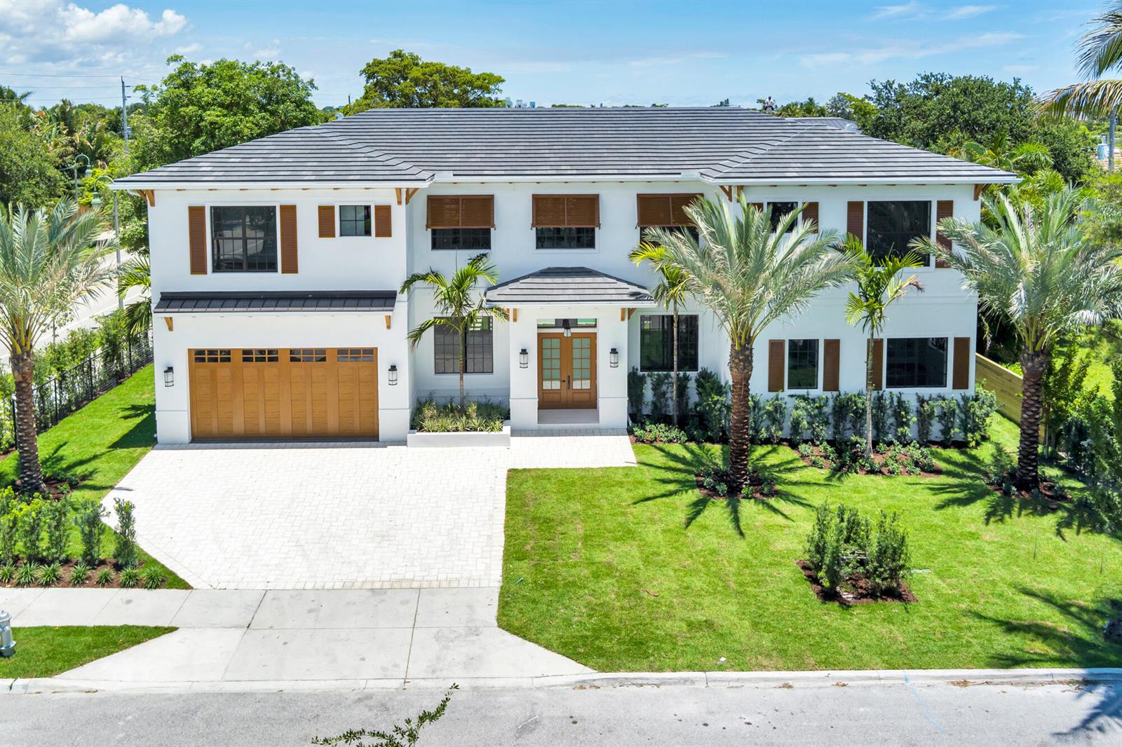 A two-story white house with a dark tiled roof, wooden garage door, and palm trees — 261 Rutland Boulevard, West Palm Beach FL 33405, WEST PALM BEACH, FL