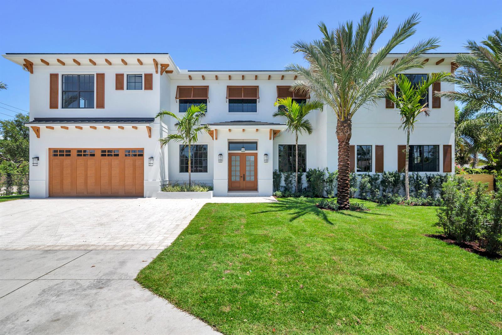 A two-story white house with a wooden garage door, shutters, and palm trees — 261 Rutland Boulevard, West Palm Beach FL 33405, WEST PALM BEACH, FL