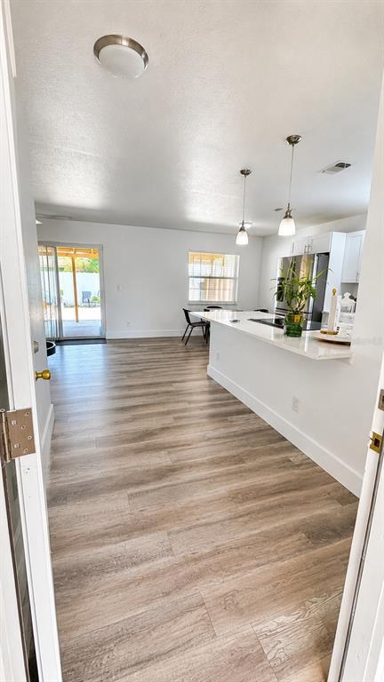 An open-concept kitchen and living area features light wood-look flooring and a white breakfast bar — 11105 N 22ND STREET, TAMPA, FL