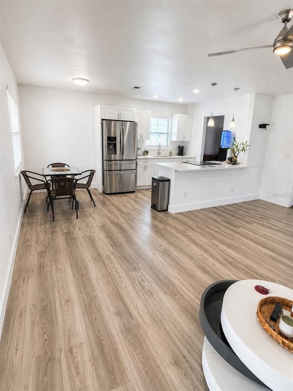 A kitchen with stainless steel appliances, white cabinetry, and a dining area with wood flooring — 11105 N 22ND STREET, TAMPA, FL