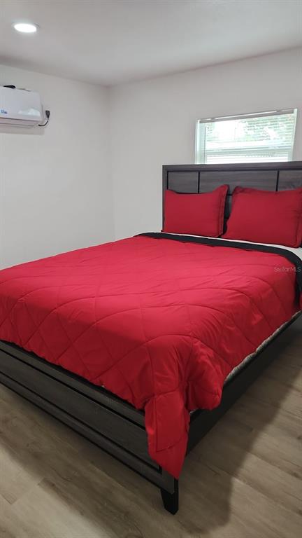 A bedroom features a dark wood bed frame with a bright red comforter and pillows — 11105 N 22ND STREET, TAMPA, FL