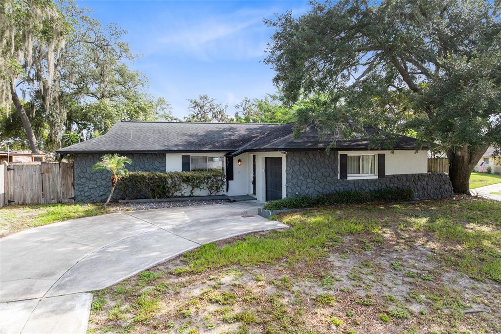 A single-story house features a dark stone facade, white trim, and a concrete driveway — 611 PHEASANT AVENUE, LONGWOOD, FL