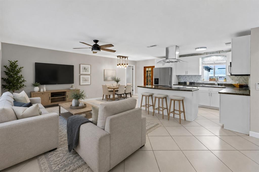 An open-concept living room and kitchen featuring tile flooring, white cabinetry, and a breakfast bar — 611 PHEASANT AVENUE, LONGWOOD, FL