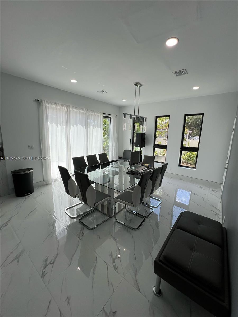 A dining room features a glass table, modern chairs, white marble floors, and tall windows — 2342 Mckinley St # 3, Hollywood FL 33020, HOLLYWOOD, FL