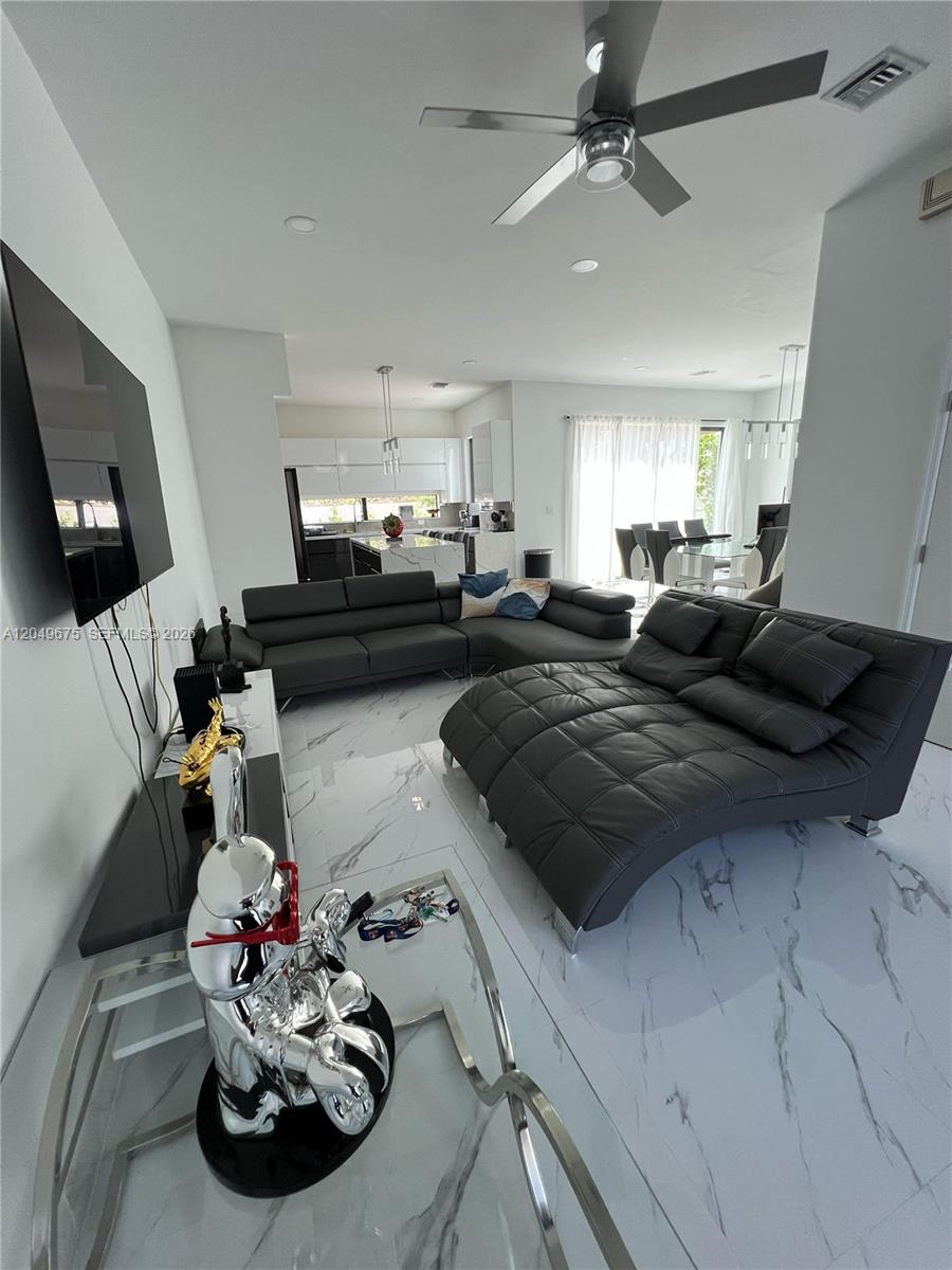 A modern living room features white marble floors, a grey sectional sofa, and a chaise lounge — 2342 Mckinley St # 3, Hollywood FL 33020, HOLLYWOOD, FL