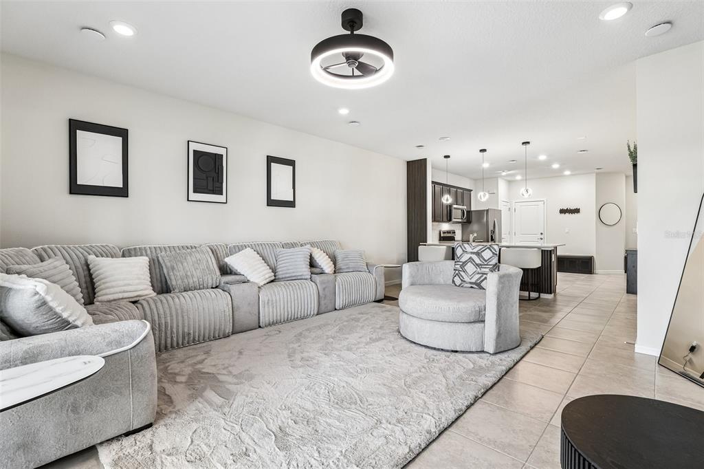 A living room features a large gray sectional, a round chair, and an open kitchen — 2570 WINSOME WAY, DAVENPORT, FL